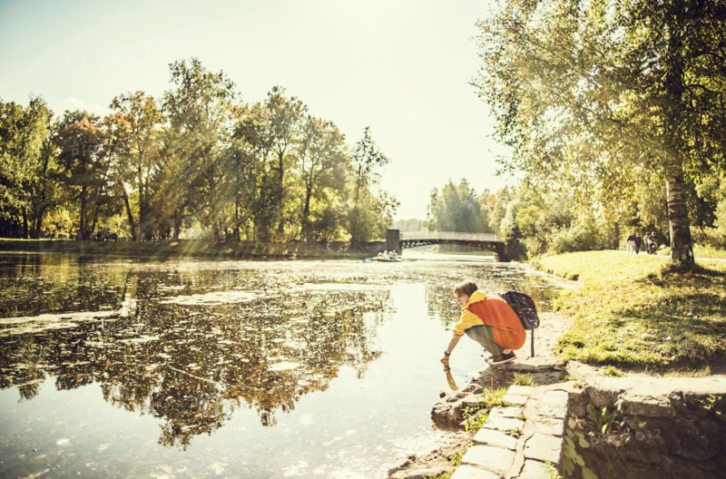 Caucasian woman dipping hand in park pond