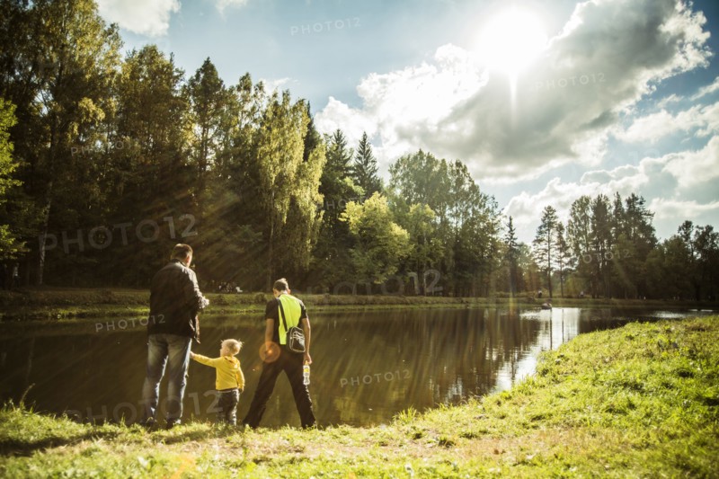 Caucasian father and sons playing near park pond