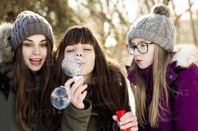 Caucasian girls blowing bubbles outdoors in winter