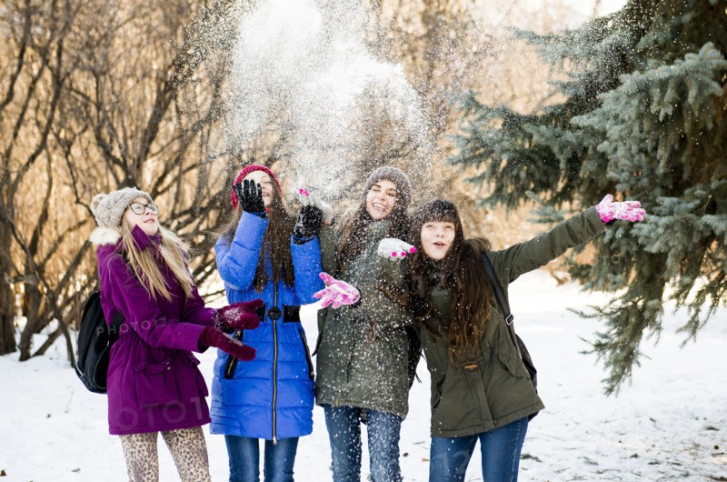 Caucasian girls throwing snow in field