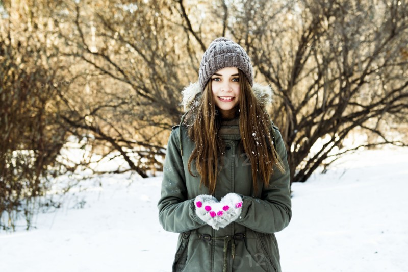 Caucasian girl holding snow in field