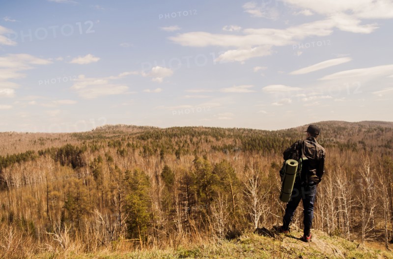 Caucasian man with camping gear overlooking rural forest