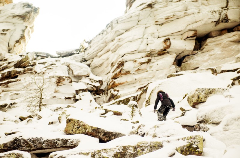 Caucasian hiker climbing snowy rock formations