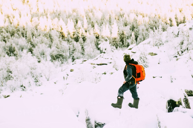 Caucasian hiker climbing snowy rock formations