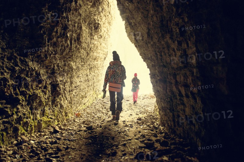 Caucasian hikers walking in rocky cave