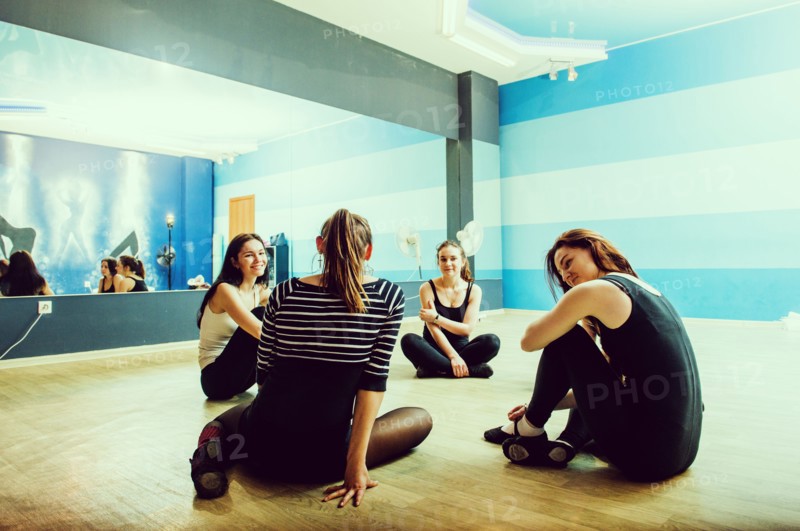 Caucasian dancers sitting on studio floor