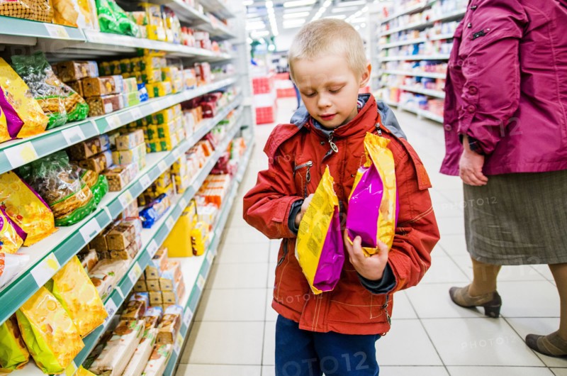 Caucasian boy examining bags of food in grocery store