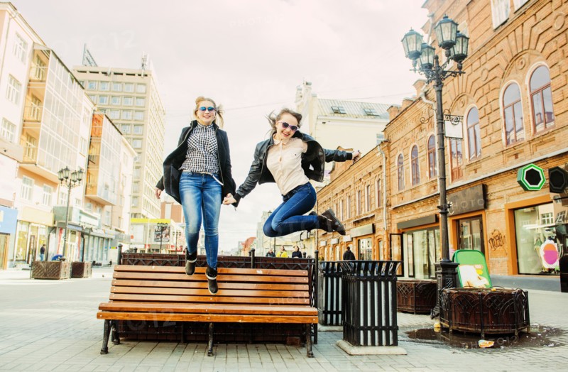 Women jumping for joy near bench