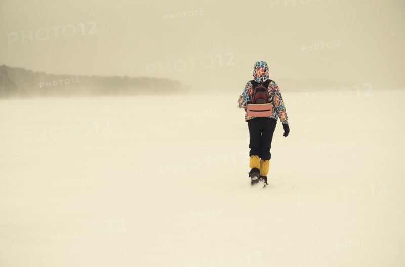 Caucasian hiker walking in snowy remote field