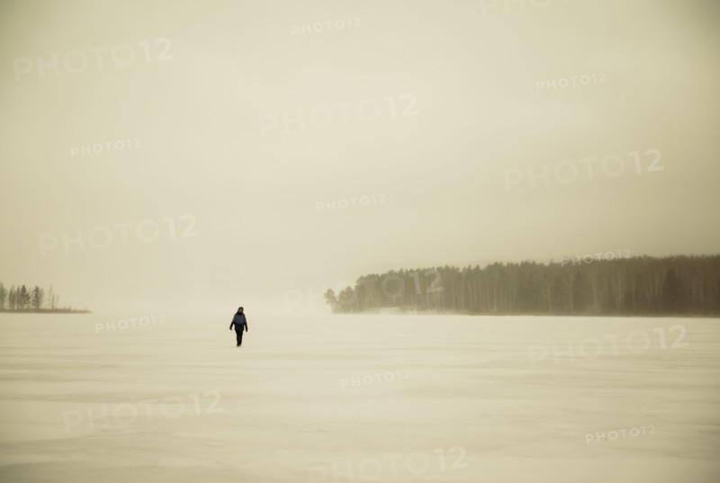 Caucasian hiker walking in snowy remote field