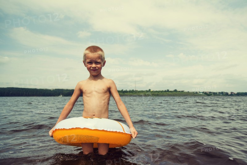 Caucasian boy playing in inner tube in lake