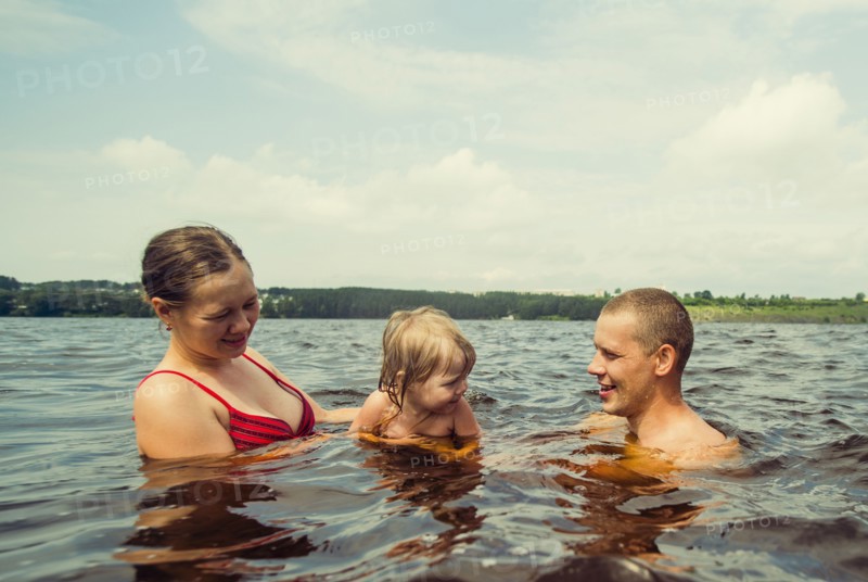 Caucasian family swimming in lake