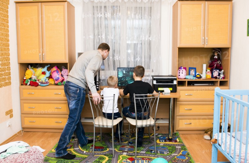 Caucasian father and sons using computer in bedroom
