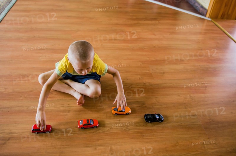 Caucasian boy playing with toy cars on floor