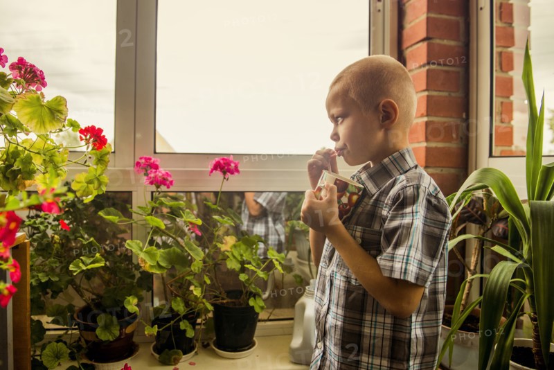 Caucasian boy drinking juice from mug by window