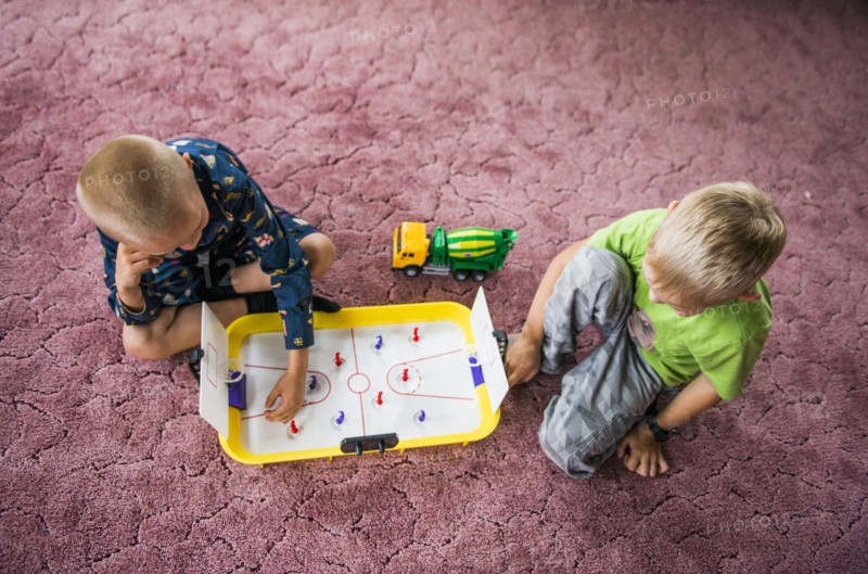 Caucasian brothers playing hockey game on floor