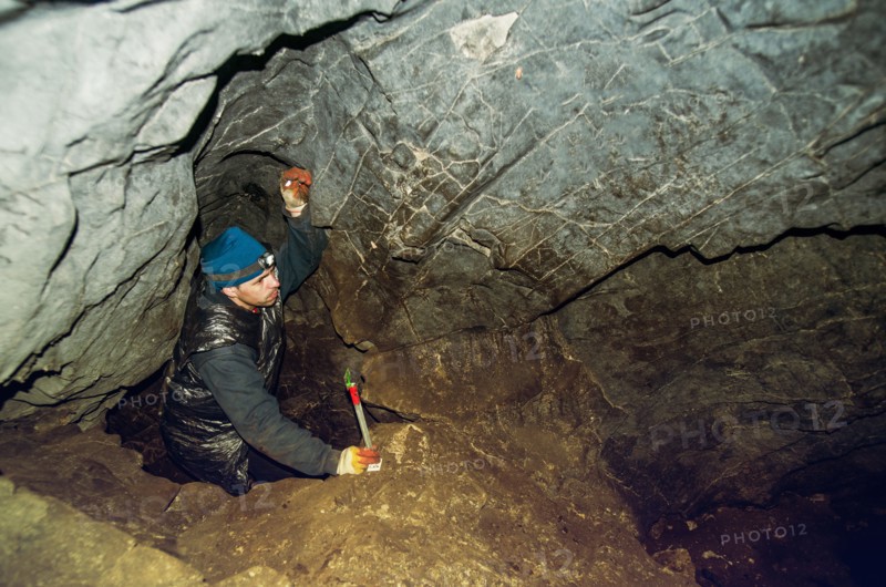 Caucasian climber exploring rock cave
