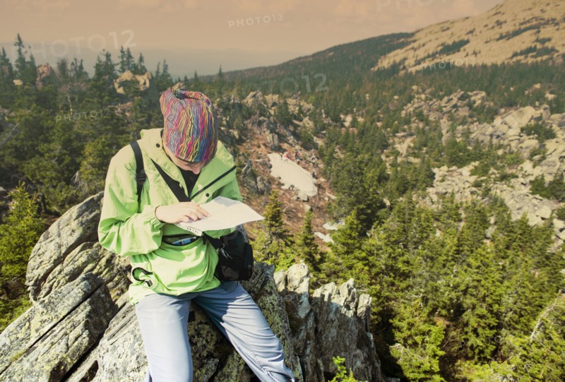 Caucasian hiker reading map on hilltop