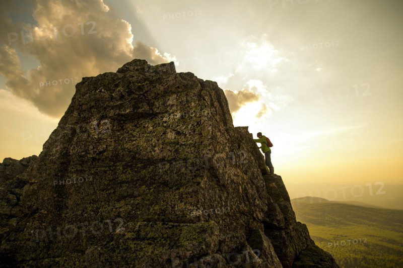 Caucasian hiker climbing on rock formation