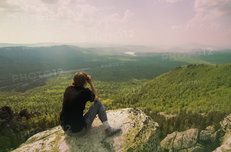 Caucasian hiker admiring remote landscape from rocky hilltop