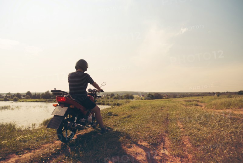 Caucasian man riding motorcycle in rural field