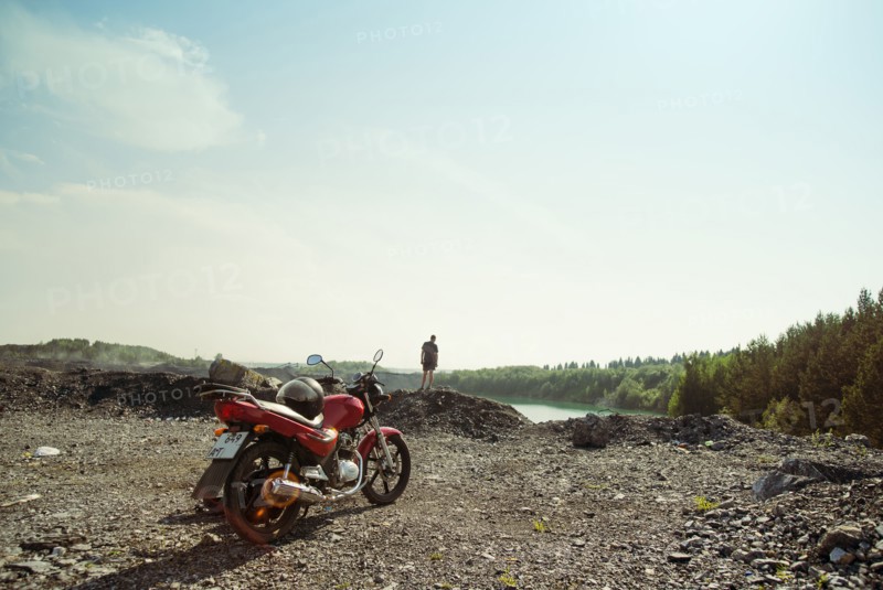 Caucasian man and motorcycle in rural field