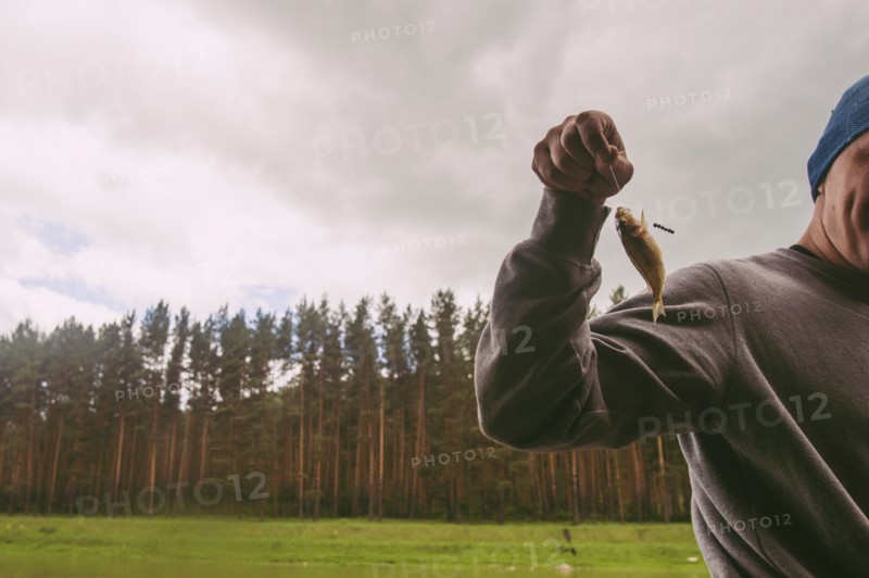 Fisherman holding small fish on hook