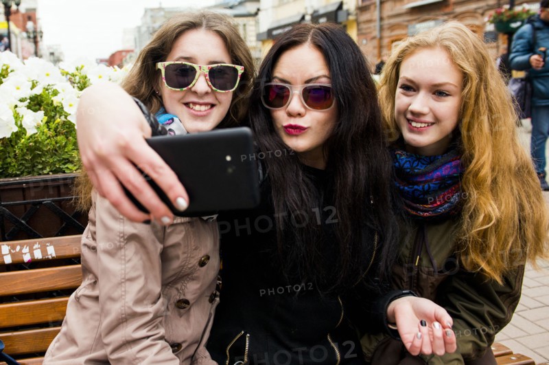 Caucasian women taking selfie on bench
