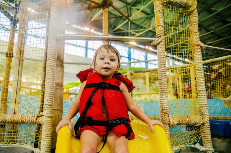 Caucasian girl riding slide at water park