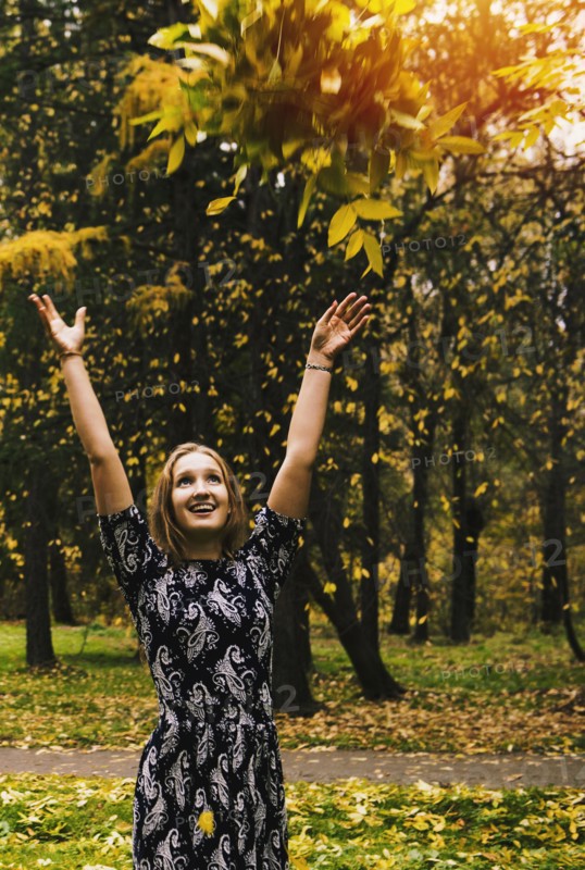Caucasian woman tossing autumn leaves in park