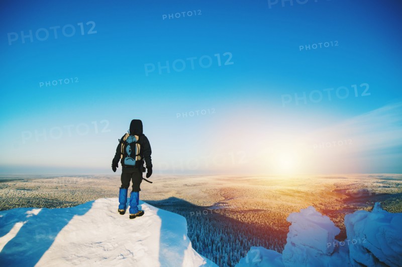 Hiker admiring view from snowy hilltop