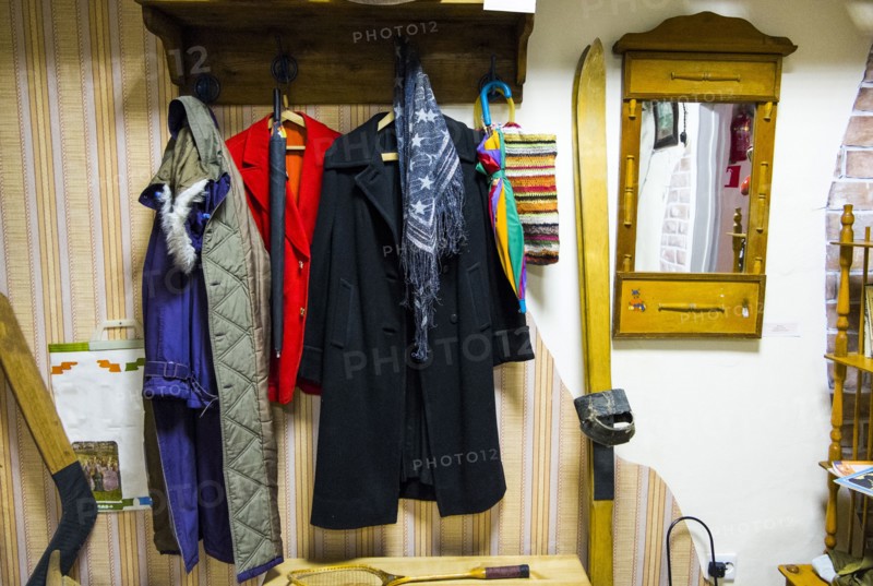 Coats on coathanger near skis and hockey stick