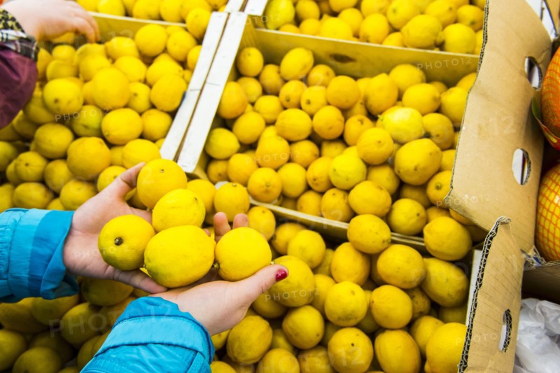 Hands of woman holding lemons from box