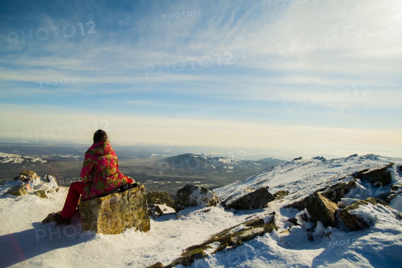 Woman hiker sitting on mountain rock in winter