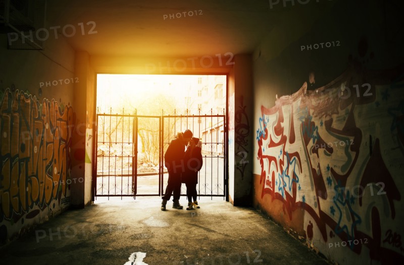 Couple kissing near graffiti at urban gate