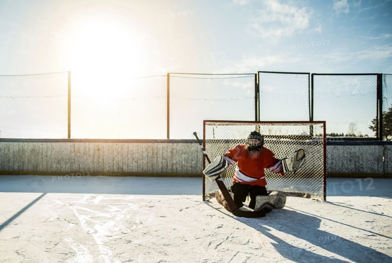 Caucasian boy playing goalie in ice hockey outdoors