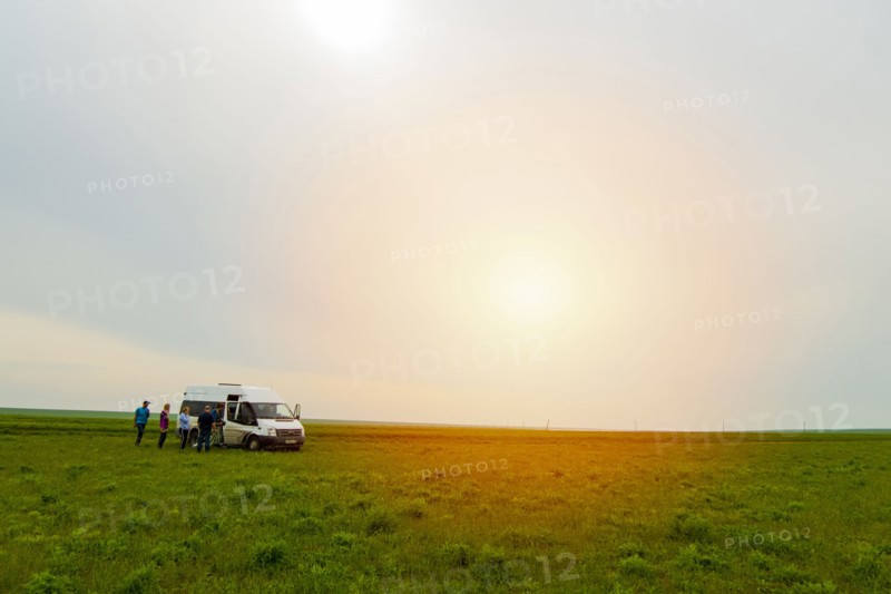 Caucasian friends standing in field near van