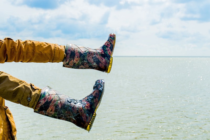 Person wearing boots on hands over water
