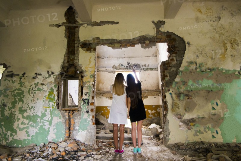 Women standing in doorway of dilapidated building
