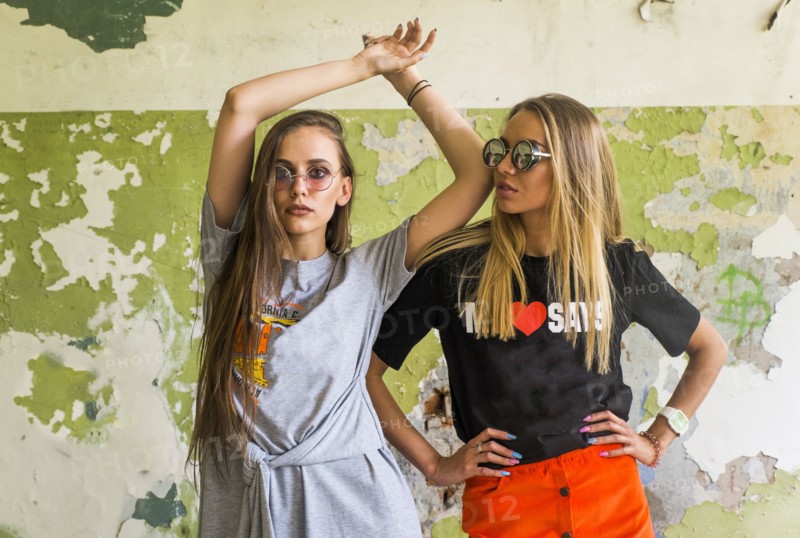 Women standing near dilapidated wall