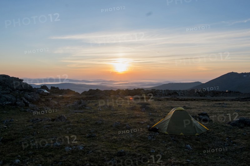 Camping tent in barren field at sunset
