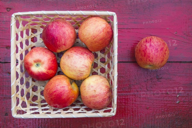 Close up of basket of red apples on red wooden table