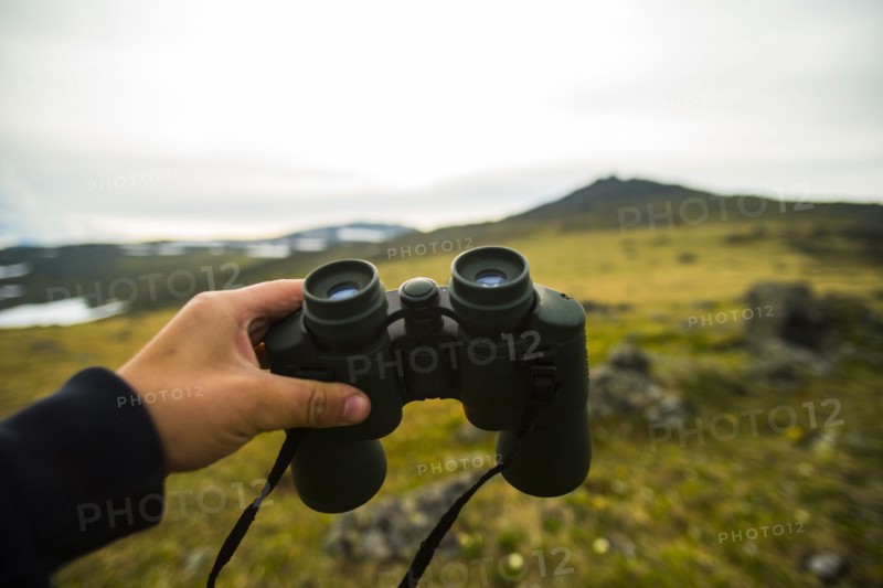 Hand of man holding binoculars outdoors