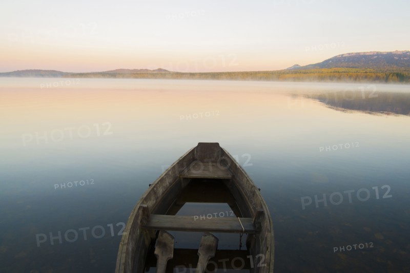 Empty rowboat on lake at sunset