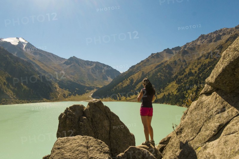 Caucasian woman standing on rocks near mountain lake