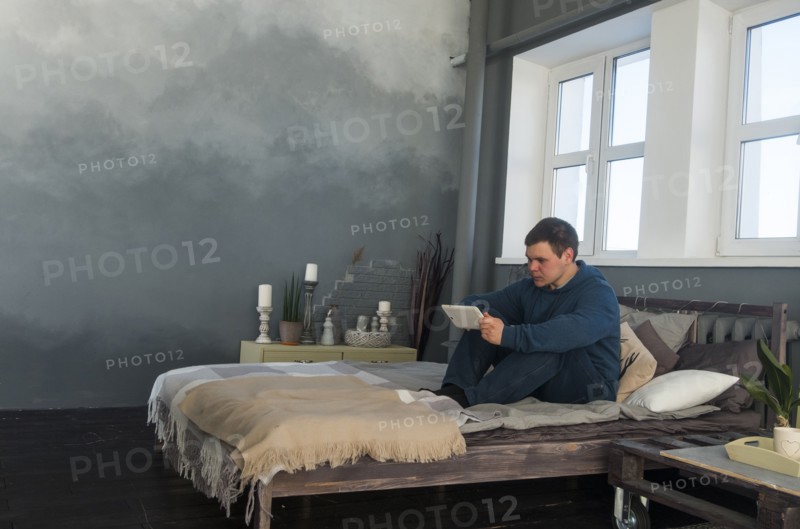 Caucasian man sitting in bed using digital tablet