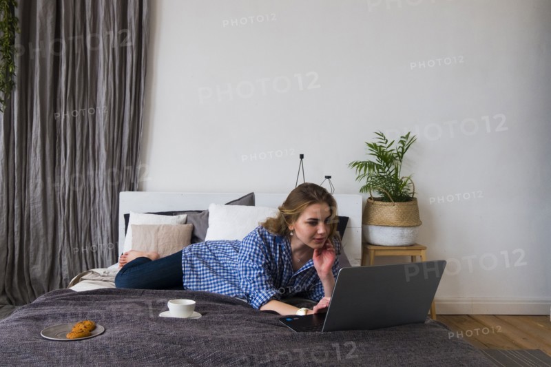 Caucasian woman laying on bed using laptop
