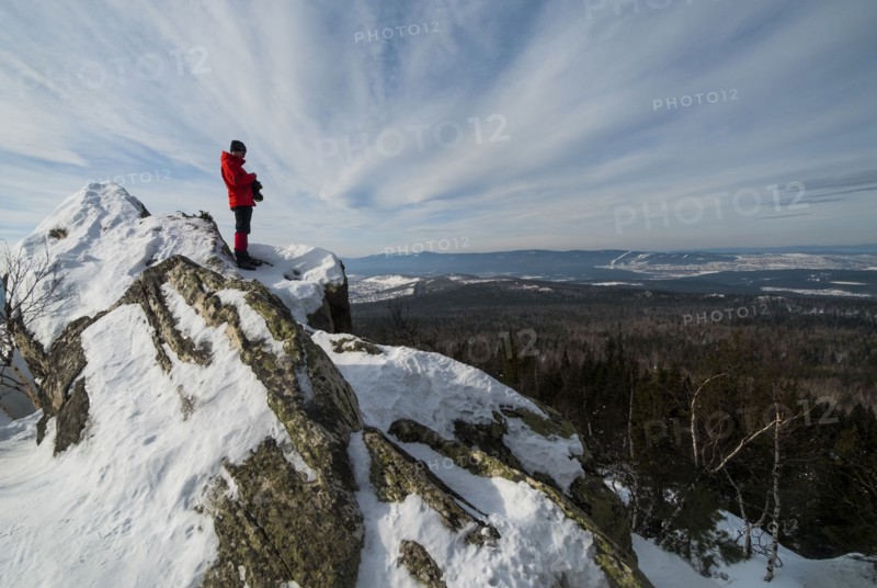 Caucasian man standing in snow admiring scenic view of forest