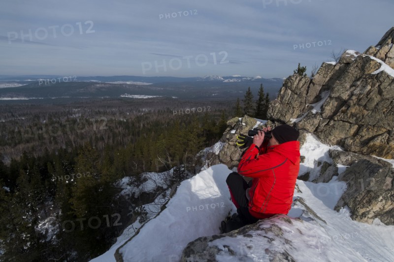 Caucasian man sitting in snow admiring scenic view of forest