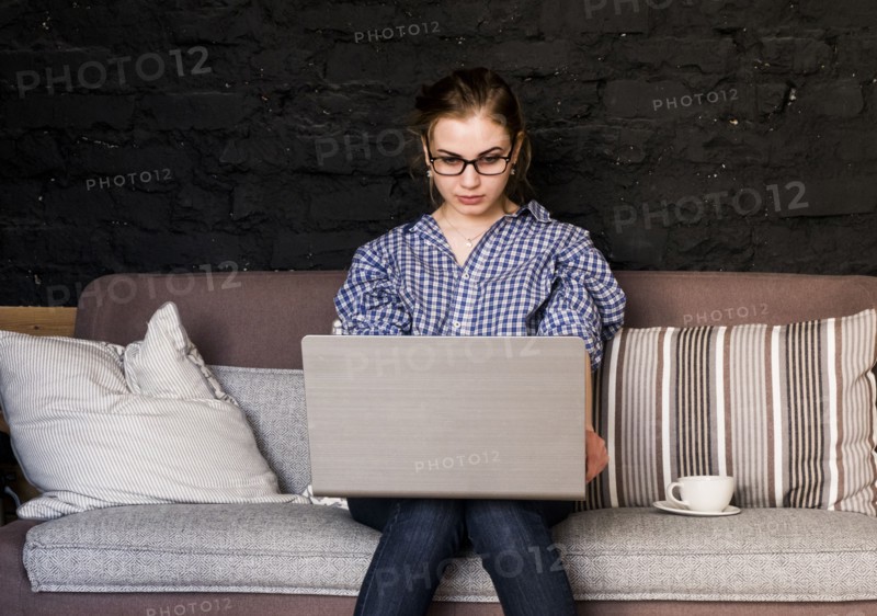 Caucasian woman sitting on sofa using laptop